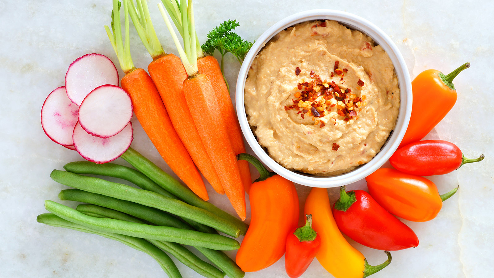 houmous avec légumes frais, vue du dessus sur marbre blanc